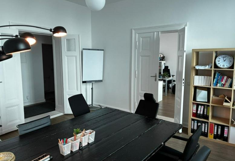 Spacious meeting room at 103, Chausseestraße featuring a large black table and natural light from large windows.