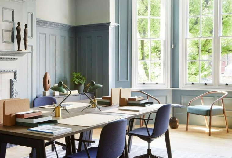 Spacious office featuring a striped rug, blue chairs, and large windows overlooking trees.