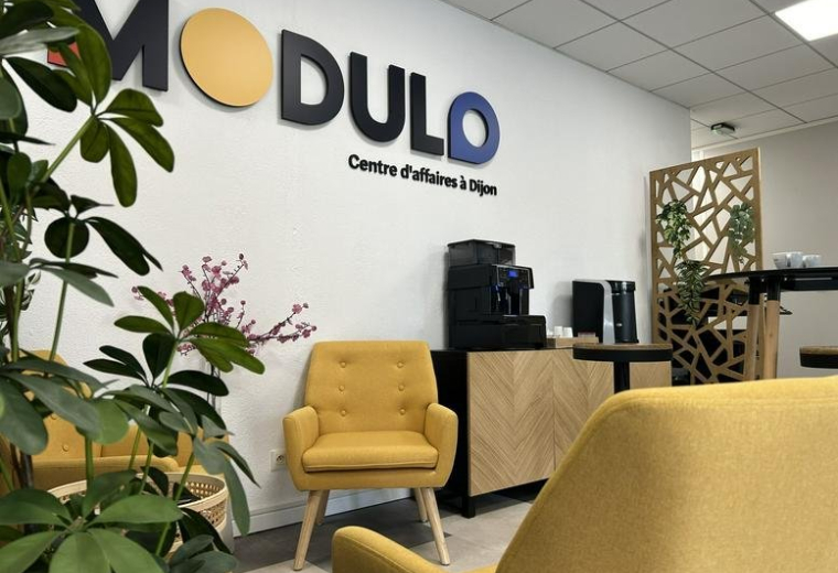 Bright reception area at 14E, Rue Pierre de Coubertin, with yellow armchairs and branded wall signage.