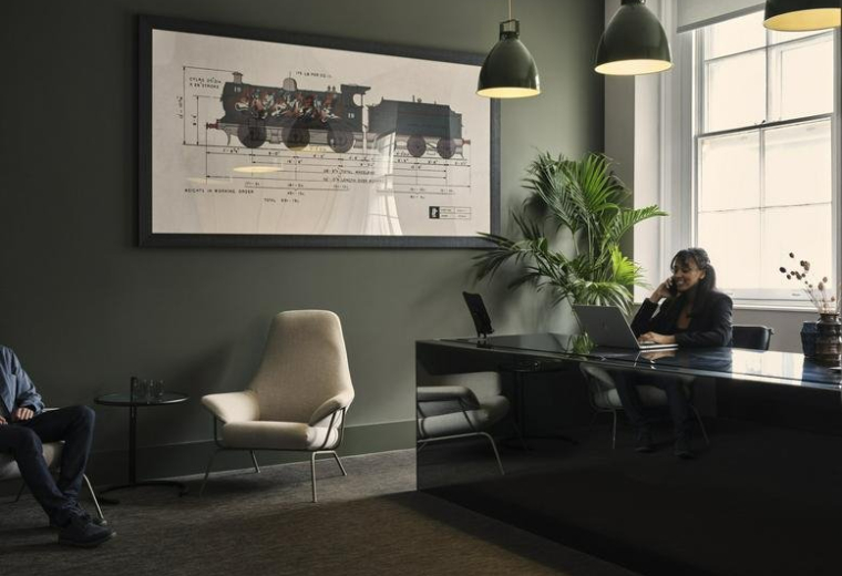 Reception lounge at 19 Eastbourne Terrace with a large steam train blueprint and plush armchair.