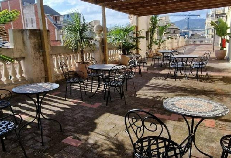 Spacious rooftop terrace at 190, Carrer de Pau Claris with bistro tables and potted palm trees.