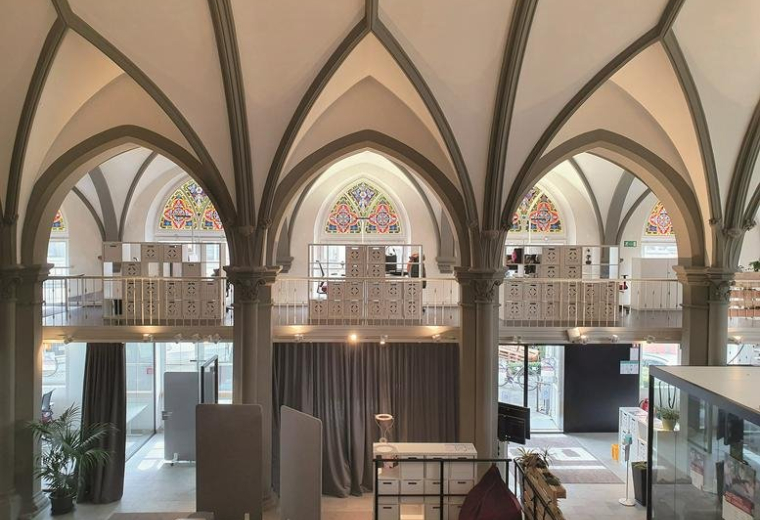Bright, open-plan workspace at 1B, Brückengasse featuring dramatic Gothic arches and mezzanine levels.