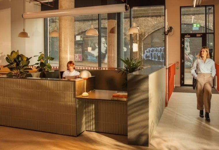 Reception area at Laundry Studios featuring a wooden desk and people moving through the space.