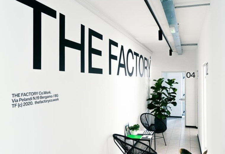 Bright lobby with bold branding at THE FACTORY Co.Work, 21 Via Luigi Pelandi.