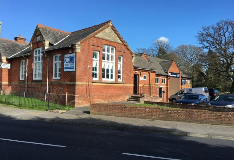 Exterior view of the red brick building at 216 Barnes Lane with large arched windows and clear blue sky.