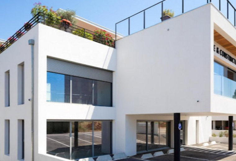 Exterior view of the modern white office building at 2390, Route des Milles with a rooftop garden.