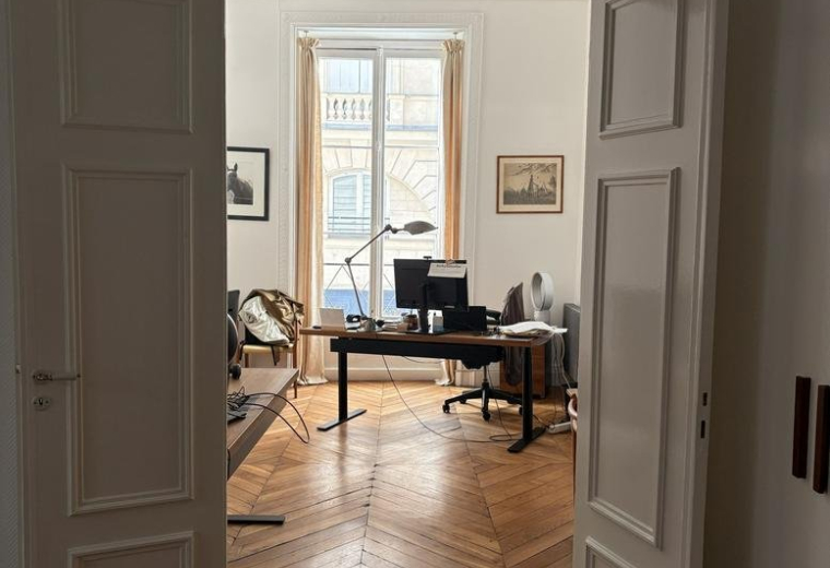 Entryway view of an office at 26, Rue de Richelieu, featuring chevron wood floors and tall windows.