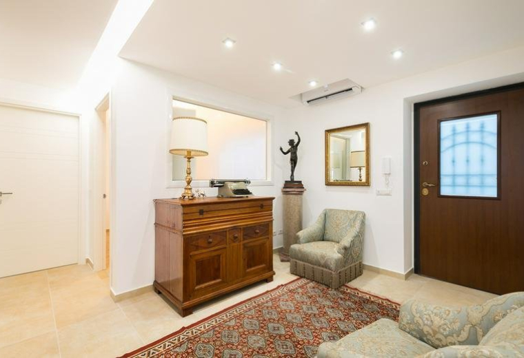 Spacious reception area at 28, Via Pietro Ferrigni featuring a wooden dresser and patterned rug.