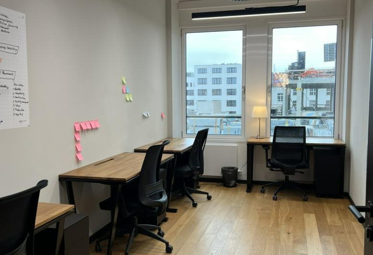 Private office at 32 Uhlandstraße with wooden desks, ergonomic chairs, and large windows with city views.