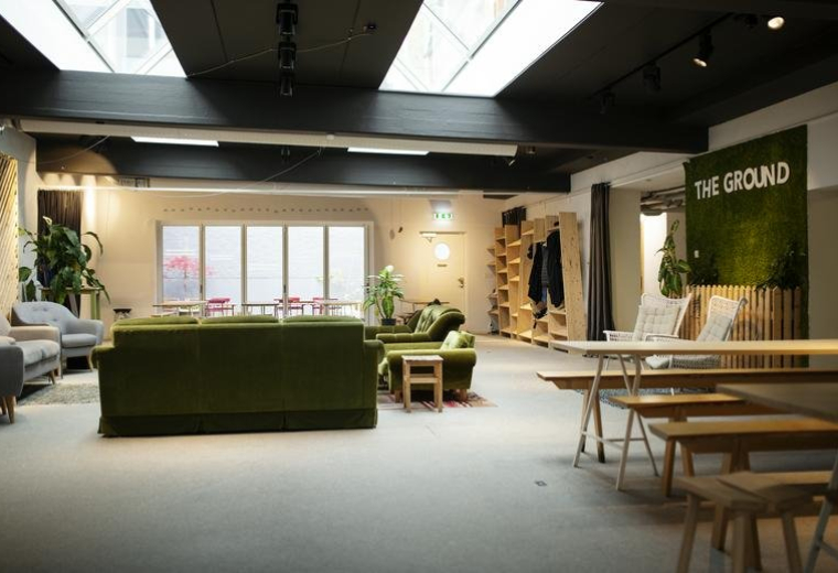 Spacious common area at 4, Bredgatan with green velvet sofas and natural light from large skylights.