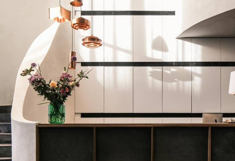 Reception area at 6, Avenue des Arts featuring a dark stone desk and copper pendant lighting.