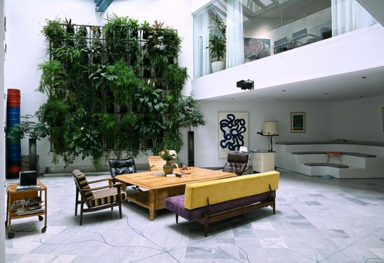 Spacious communal lounge at 7, Marokkanergasse, featuring a massive living plant wall and modern furniture.