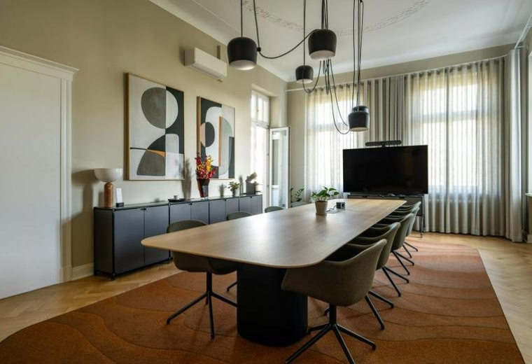 Large conference room with a long wooden table, modern lighting, and abstract wall art.