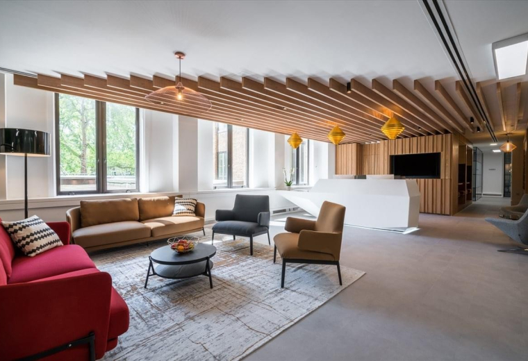 Sleek lounge at Berkeley Square House with a red sofa and architectural ceiling slats.
