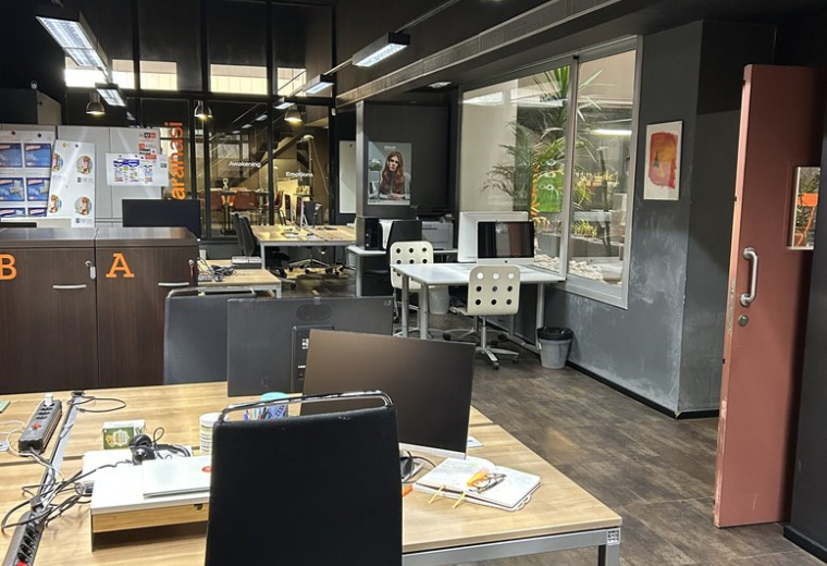 Open-plan workspace at Carrer de Pujades,146 featuring wooden desks and black ergonomic chairs.