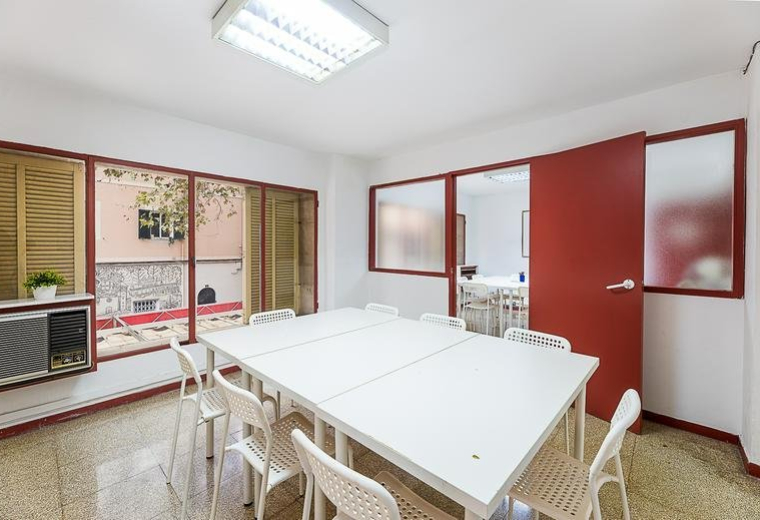 Meeting room at Carrer Guillem Costa featuring a white table, red sliding door, and courtyard views.