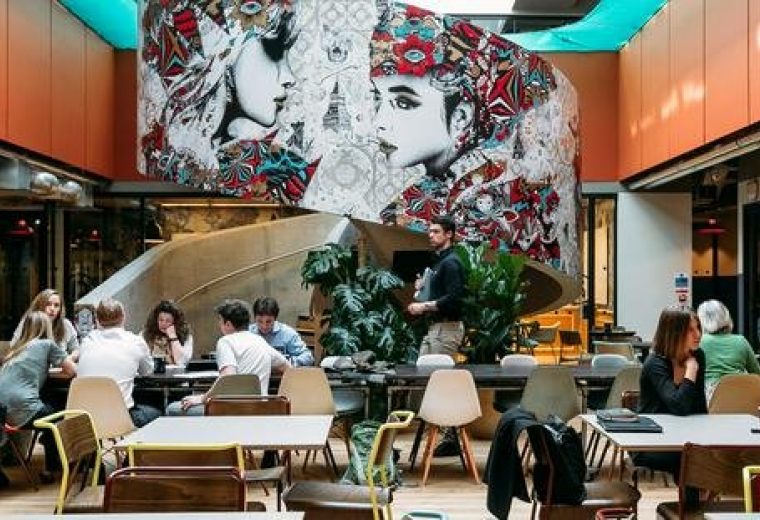 Spacious lobby at Castellana 43 with a large artistic mural and vibrant orange architectural details.