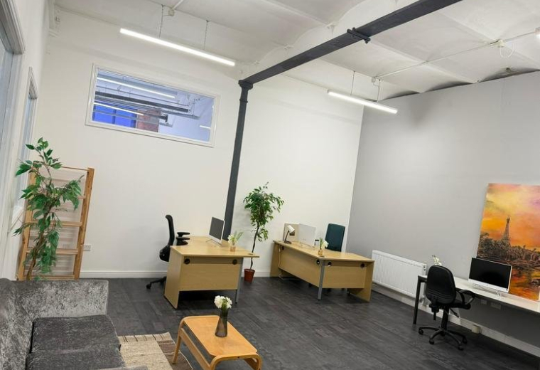 Spacious open-plan office at Crown Street with wooden desks, indoor plants, and natural light.