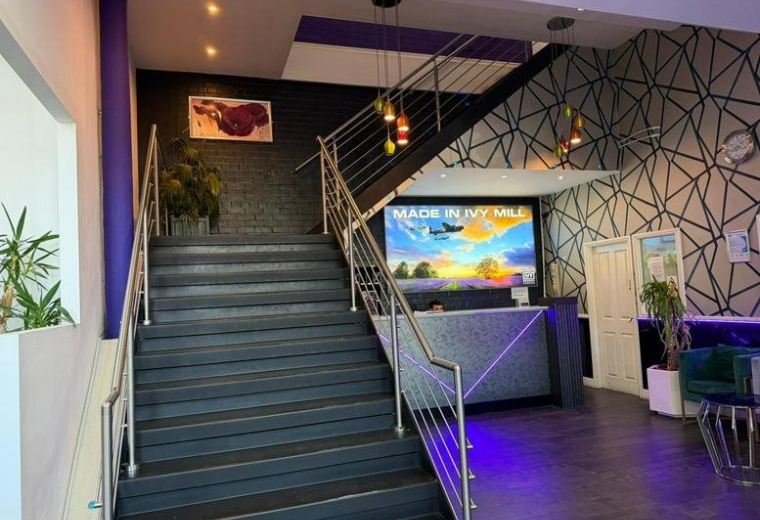 Modern reception lobby at Crown Street featuring a grand staircase and vibrant purple lighting.