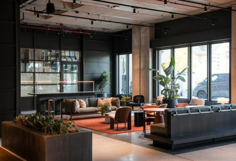 Spacious communal lounge at Deal Porters Way with modern seating, warm rugs, and industrial ceilings.