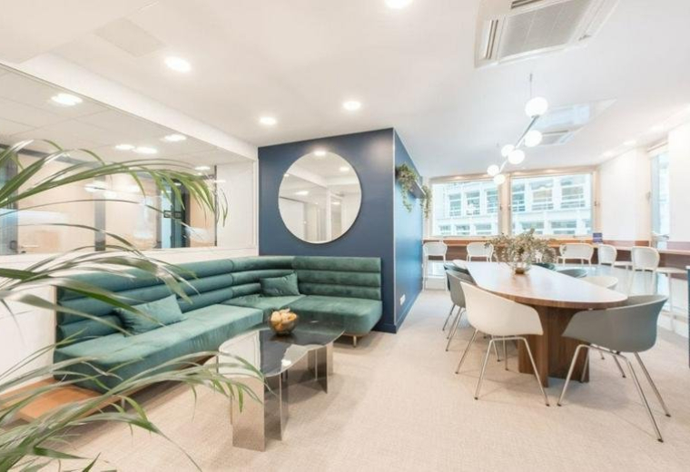 Spacious communal lounge at Elysees Montaigne, 42 Avenue Montaigne featuring a teal sofa and navy feature wall.