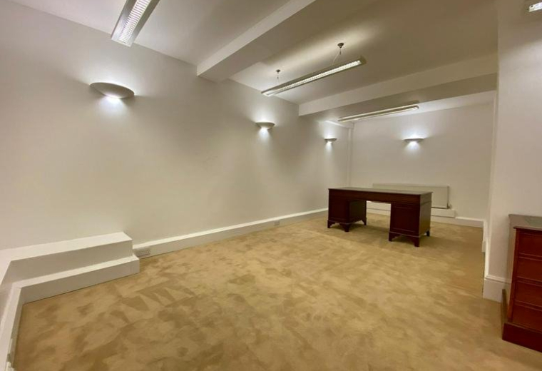 Spacious private office at Grosvenor Gardens with white walls and a dark wood executive desk.