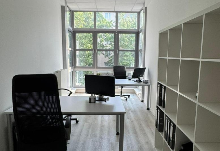 Private office at Huttenstraße with two desks, ergonomic chairs, and large windows.