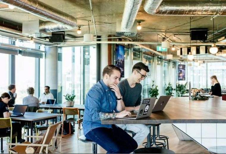 Large open-plan office area with modern industrial ceilings and various seating zones.