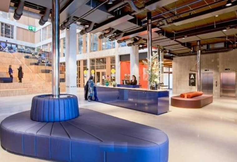 Modern lobby at Nordenskiöldsgatan 24, Malmo with a sleek blue reception desk and unique curved seating.