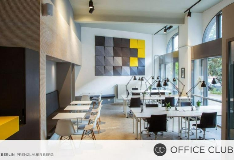 Spacious coworking area with long desks and a colourful geometric feature wall at Pappelallee 78/79.