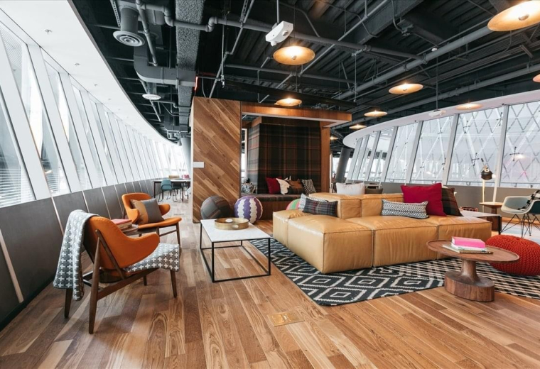 Spacious communal lounge at Paseo De La Castellana 77 with modern furniture and floor-to-ceiling windows.