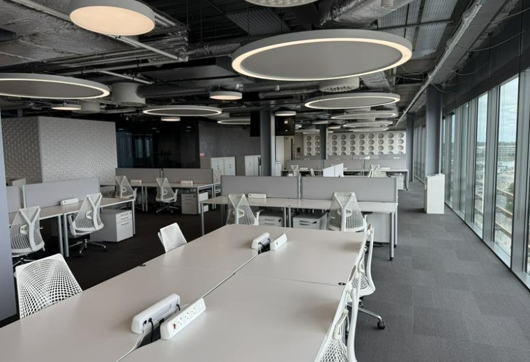 Spacious open-plan workspace at Point Village with modern white desks and circular overhead lighting.