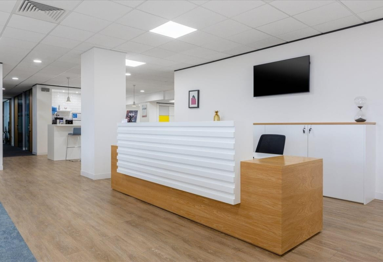 Professional reception area at Romer House with a wood-fronted desk and wall-mounted TV.