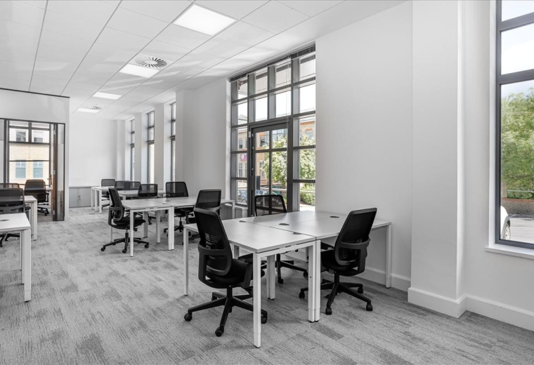 Spacious open-plan workspace at Rourke House, Watermans Business Park featuring white desks and large windows.