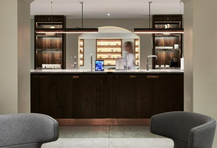 Spacious communal lounge at St Clements House, 27 Clements Lane, Central London with an arched view of a breakout bar.