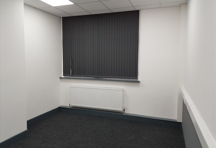 Spacious private office at Tradeforce Building with dark carpet and vertical window blinds.