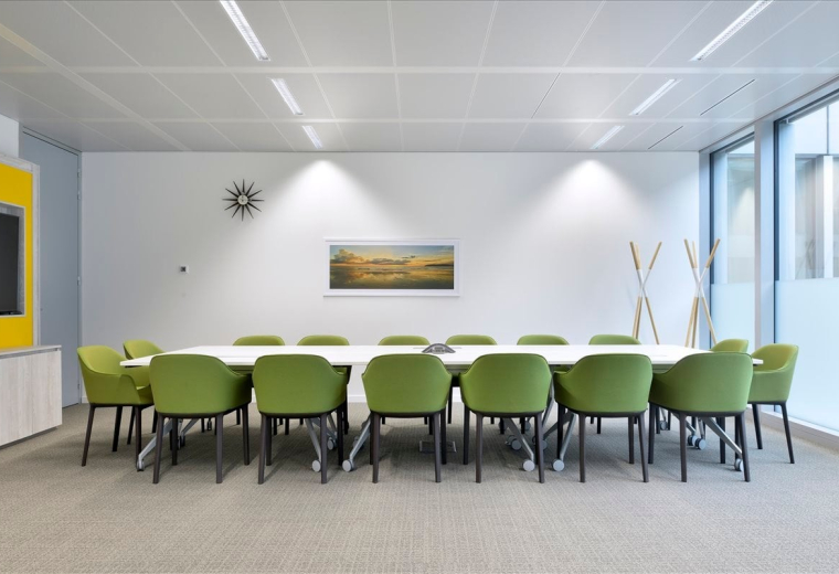 Meeting room at Via Dei Berio with lime green armchairs and a landscape painting.
