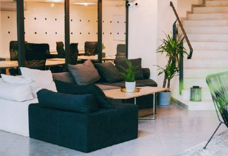 Spacious communal lounge at Ring Tower with modern sofas, a coffee table, and indoor plants.