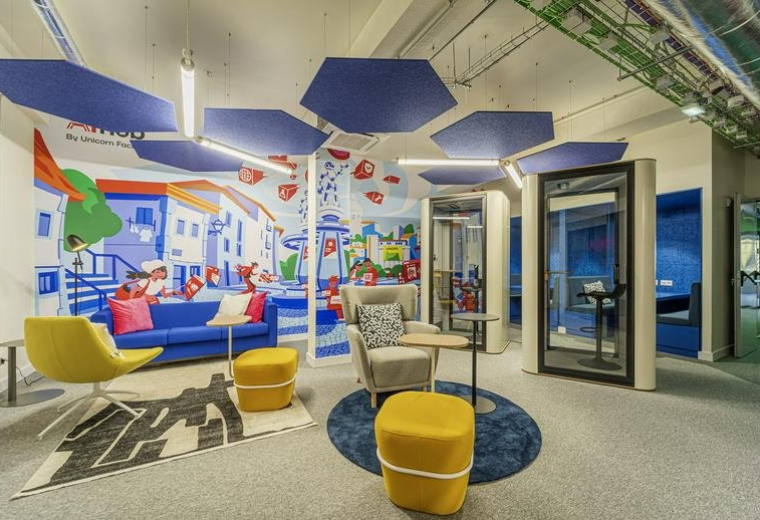 Vibrant lounge at Rua João Saraiva 34, 3, Lisboa featuring blue sofas, yellow ottomans, and colorful wall murals.