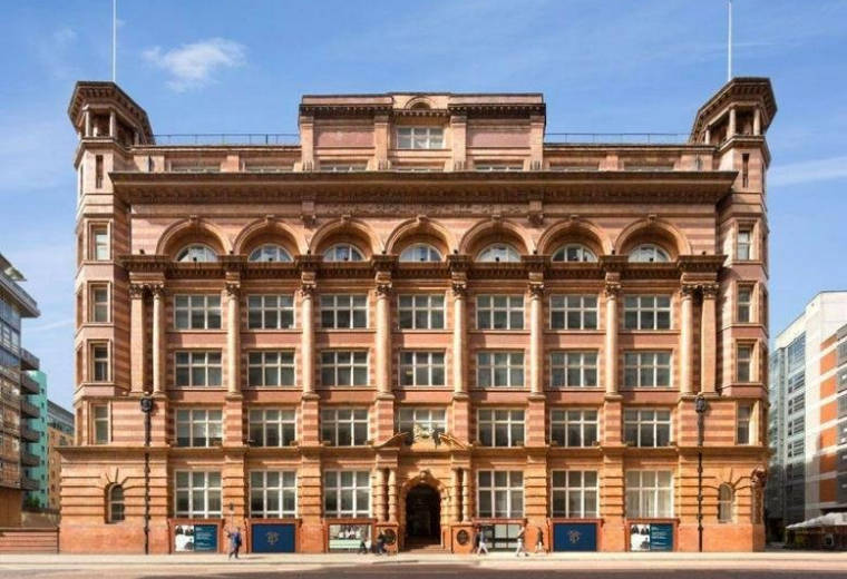Grand brick exterior of The Tootal Buildings, Broadhurst House, featuring ornate arches and twin corner towers.