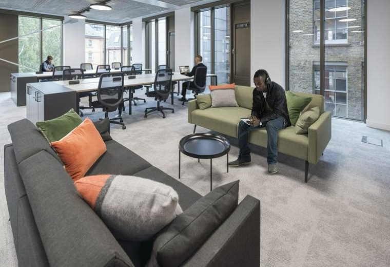 Spacious communal lounge at Verse Building, Old Street, London with sofas and views of the desk area.