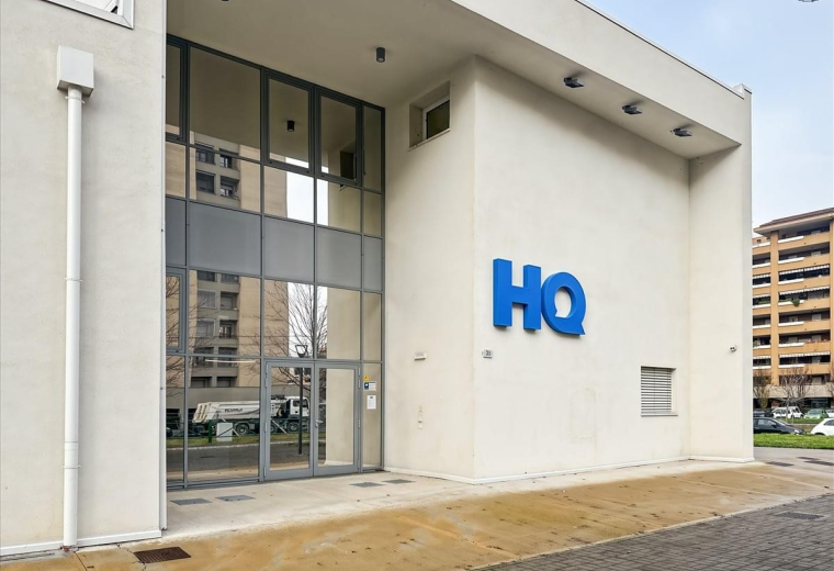 Exterior view of the modern white HQ building at Via Roberto Tremelloni 31.