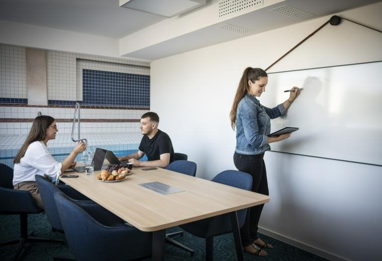 Bright conference room with a woman writing on a large whiteboard.