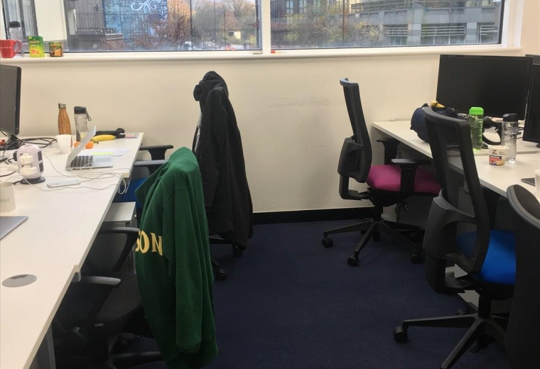 Open-plan office at Tower Bridge Business Centre with workstations, ergonomic chairs, and large windows.