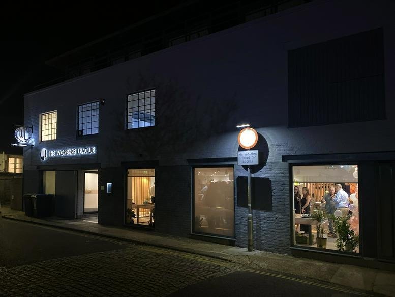 Exterior view of the office building at night with warm lights glowing through large ground-floor windows.