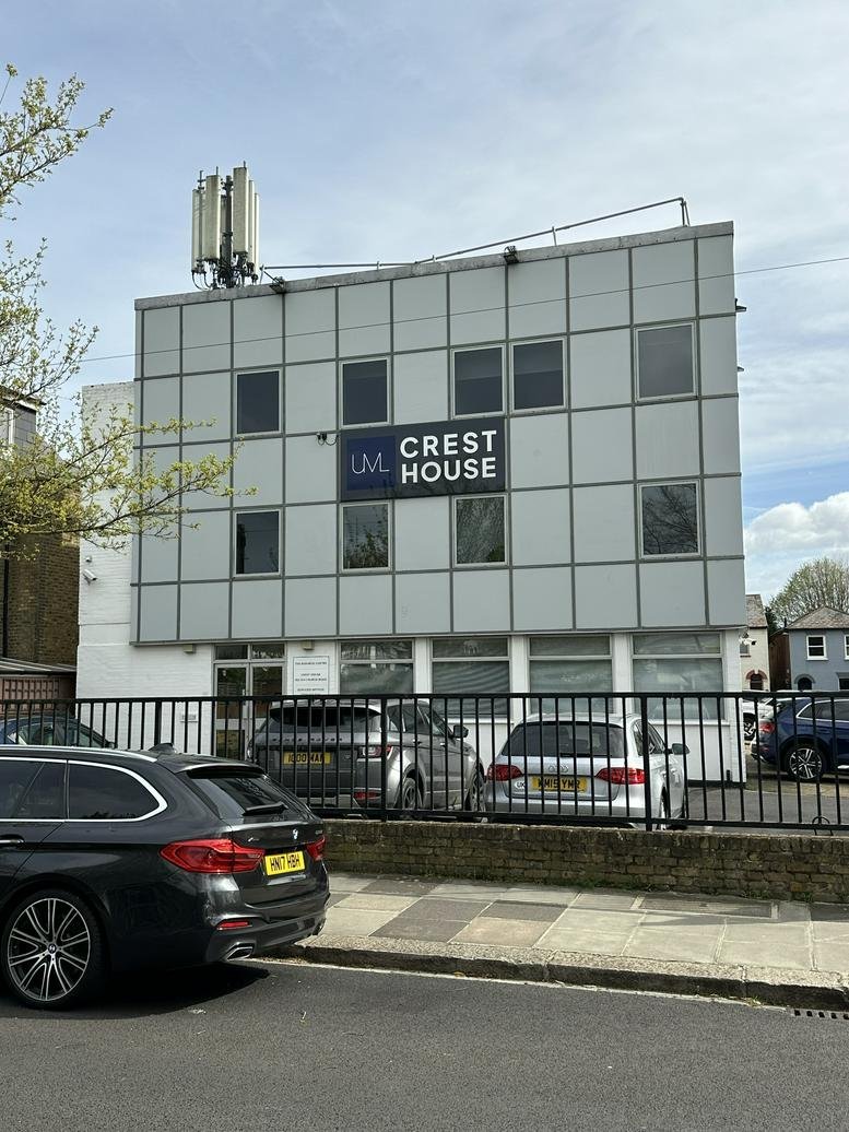 Exterior view of the grey-facade building at Crest House with parking in front.