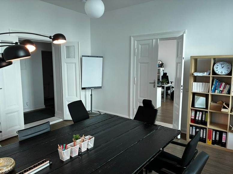 Spacious meeting room at 103, Chausseestraße featuring a large black table and natural light from large windows.