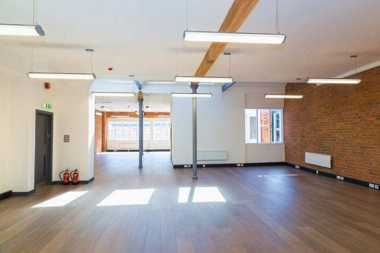 Spacious open-plan common area at 109, Portland Street with wooden beams and polished floors.