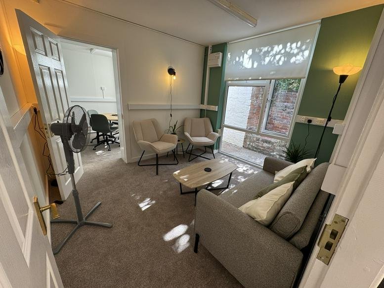 Lounge area at 11 Broad Street with grey sofa, armchairs, and a green feature wall.