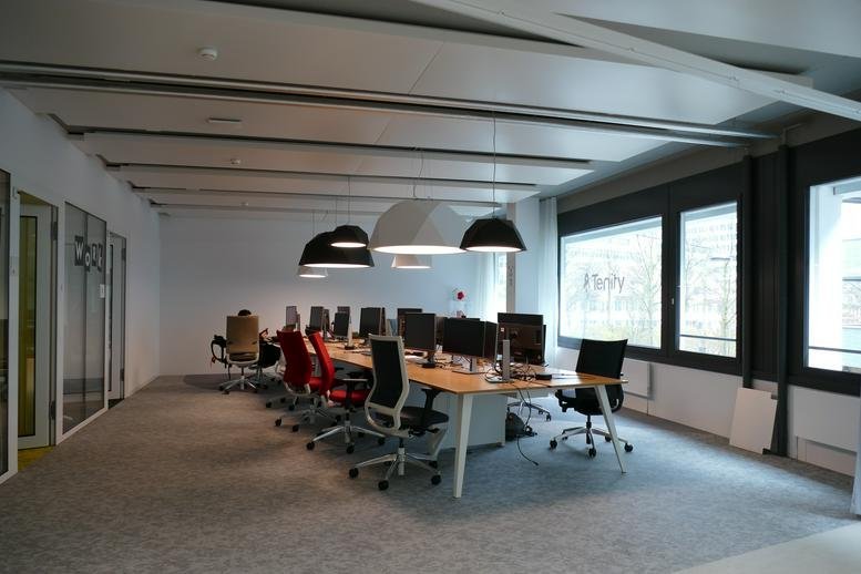 Spacious open-plan workspace at 110, Pfingstweidstrasse with pendant lights and rows of desks.